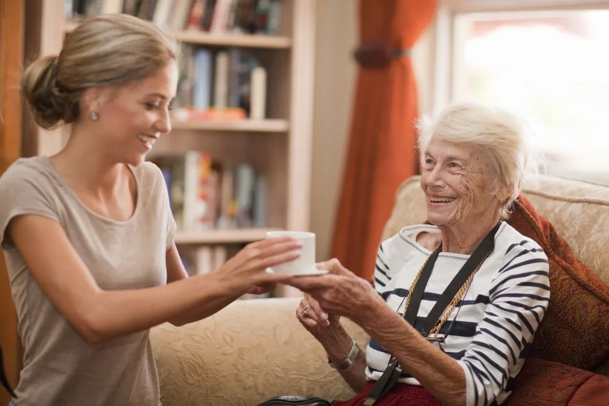 care assistant handing coffee mug to senior resident