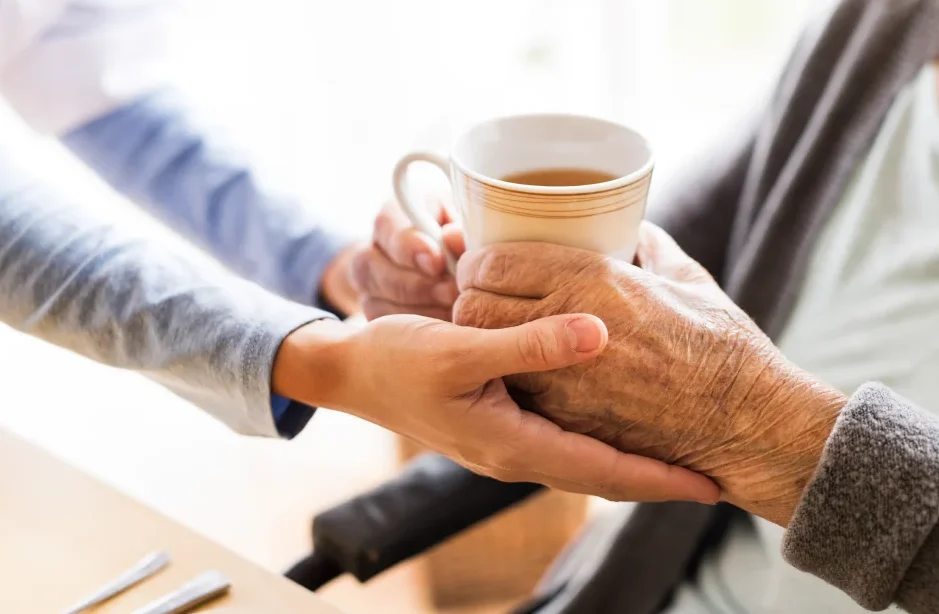 health visitor giving senior woman tea during visit