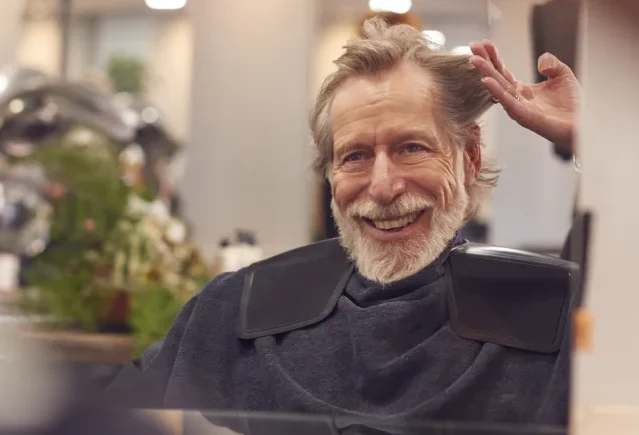 senior man getting haircut at the onsite barbershop