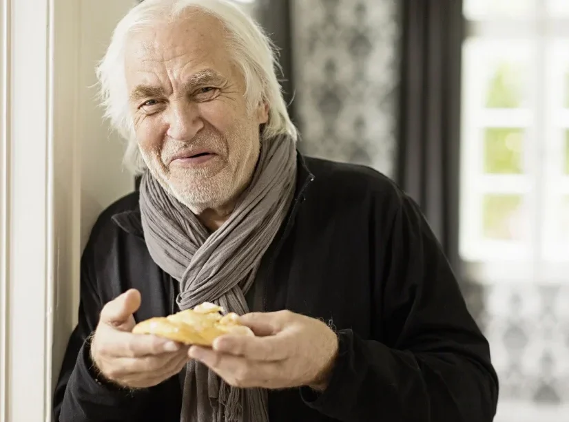 senior man smiling and enjoying a danish pastry