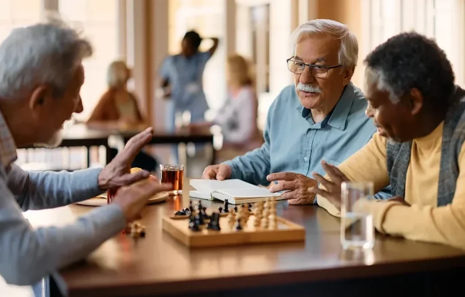 senior men talking and playing chess in the lounge