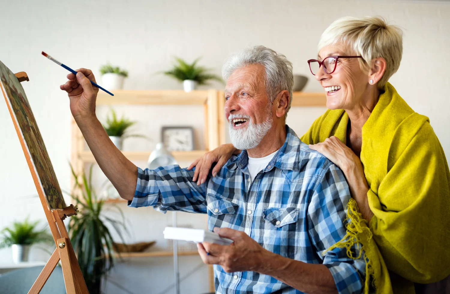 Happy senior couple having fun painting on canvas